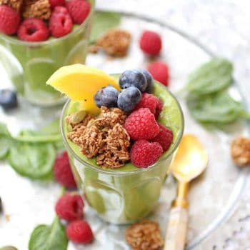 A delicious green smoothie topped with berries, granola and mango